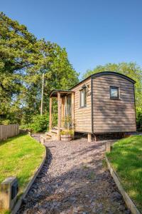 a small wooden house sitting on top of a yard at Hazel Boutique Shepherds Hut Cotswolds in Cirencester