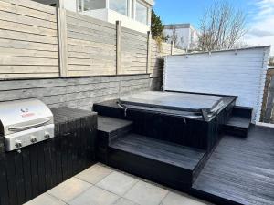 a deck with a hot tub and a grill at Ocean-Side Family Villa in Reykjavík