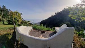 a large stone tub sitting in a field with a hill at Arambha ecovillage farmstay in Tábua
