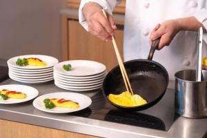 a chef cooking food in a pan on a counter at Hotel Forza Oita in Oita