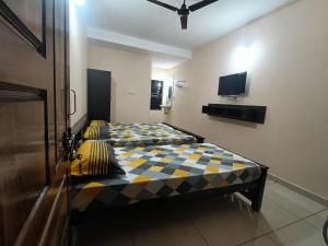 two beds in a small room with a tv at Gokula Arcade in Subrahmanya