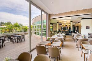 a restaurant with tables and chairs and large windows at Intercity Itupeva in Itupeva
