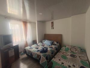 a small bedroom with a bed and a tv at Casa Bercel in Choachí