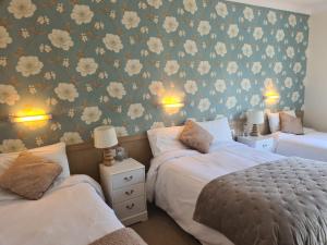 two beds in a bedroom with floral wallpaper at Shannonside House N37HF67 in Athlone +32 photos