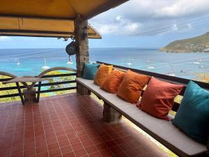 a bench with colorful pillows on a balcony overlooking the ocean at Trinity Point Hillside Villa, beach & sunset views in Bequia