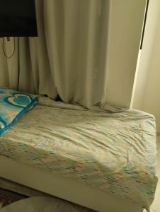 a unmade bed with a curtain and a bedsheet at Dar Fouzia in Hammamet Sud