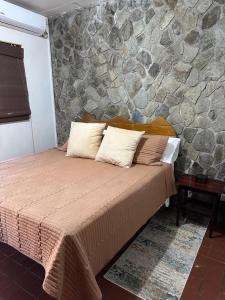 a bed in a room with a stone wall at Trinity Point Hillside Villa, beach & sunset views in Bequia +55 photos