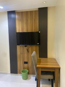 a wooden table with a chair and a television on a wall at CHASE hotels in Ibadan