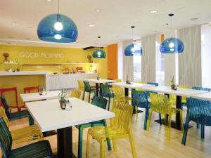 a restaurant with white tables and chairs and blue pendants at ibis Styles Duesseldorf-Neuss in Neuss