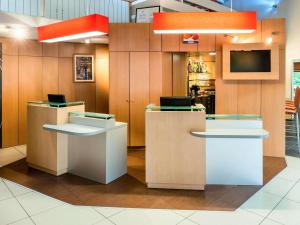 a lobby with two counters and a tv on the wall at ibis Bourg en Bresse in Bourg-en-Bresse