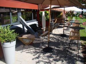 a patio with chairs and tables and an umbrella at ibis Bourg en Bresse in Bourg-en-Bresse