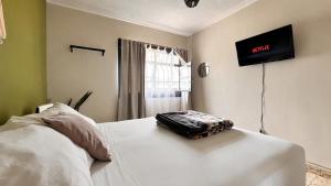 a bedroom with a white bed with a television on the wall at Lool Beh Hostal in San Miguel de Allende +21 photos