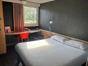 a bedroom with a bed and a desk and a window at ibis Lorient Centre Hôtelier in Caudan +54 photos