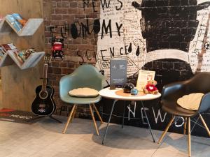 a room with two chairs and a table and a guitar at Hotel ibis Narbonne in Narbonne