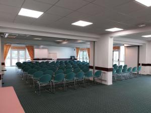 a conference room with green chairs and a podium at ibis Rambouillet in Rambouillet