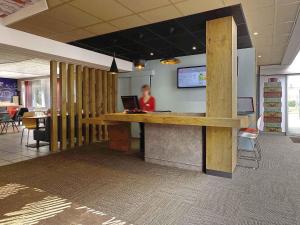 a woman sitting at a desk with a laptop at ibis Poitiers Beaulieu in Poitiers