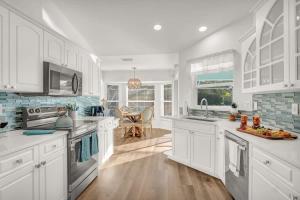a white kitchen with white cabinets and a sink at Beach Getaway - Pool & 2 King Beds in Sebastian