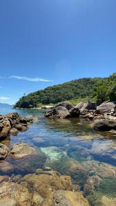 a river with rocks and water and trees in the background at Casa Recanto in Angra dos Reis