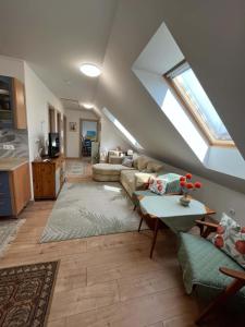 a living room with a skylight and a couch at Fenyves Appartman in Pécsely