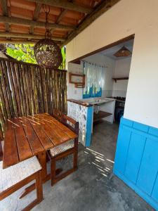 a room with a wooden table and a kitchen at Pousada Coco Dendê in Ilha de Boipeba