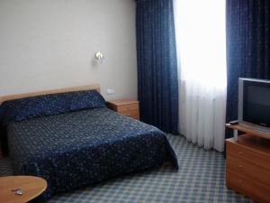 una camera d'albergo con letto e TV di Жеруйык Отель ad Aqtau