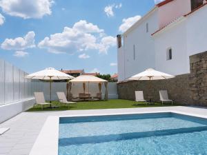 a swimming pool with chairs and umbrellas next to a building at Casa da Rabita in Capinha