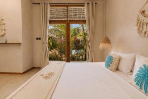 a bedroom with a white bed with a large window at The Garten Living in Paje