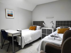 a bedroom with two beds and a desk and a chair at Glendalough Sanctuary in Brockagh