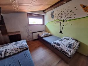 a bedroom with two beds and a tree mural on the wall at RETRO Apartmány Podhájska in Podhájska