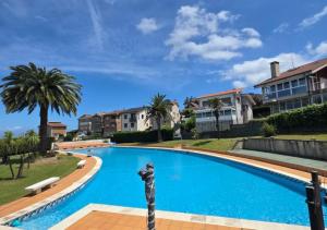 a large blue swimming pool with palm trees and houses at Xivares playa in Carrió