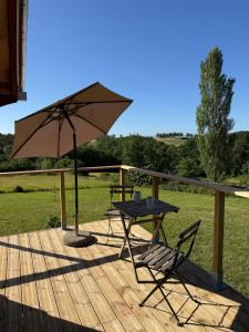 a table and a chair and an umbrella on a deck at Chambre Panoramique Bellevue in Bellegarde-Adoulins
