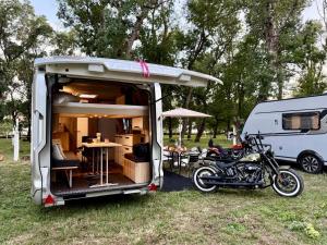 a caravan with a motorcycle parked in the grass at Neptun Beach Caravans in Ulcinj