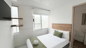 a white bedroom with a bed and two windows at Casa Mama Hotel in Manizales