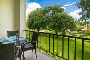 a balcony with a table and chairs and a view of a park at Chic Minimalist Condo with Swimming Pool, Hot Tub, and Beach Club Access in Coco