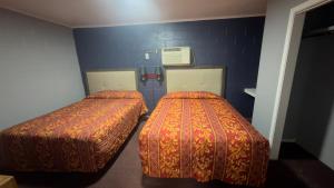 two beds in a small room with blue walls at Ada Inn & Suites in Ada