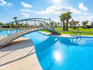 a bridge over a swimming pool with blue water at Costa Azahar - En Primera Línea in El Borseral
