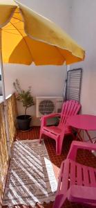 two pink chairs and an umbrella on a patio at Yemanja Guest Flat- vue Mer &Salin, piscine, climatisation in Gruissan