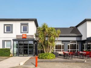 a hotel with tables and chairs in front of a building at ibis Saint-Malo Madeleine in Saint Malo