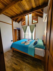 a bedroom with a bed with blue sheets and a window at Arenal Sweet Cabins in Fortuna