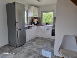 a kitchen with white cabinets and a stainless steel refrigerator at Domek na Sowiej in Kłodzko