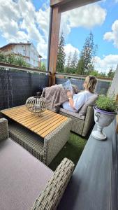 a woman sitting on a chair reading a book while holding a baby at Tatrzańska Prowansja SPA&SKI Apartamenty in Zakopane