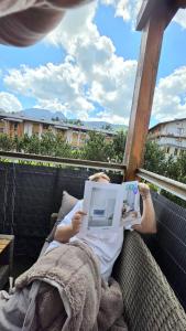 a person laying in a chair reading a book at Tatrzańska Prowansja SPA&SKI Apartamenty in Zakopane