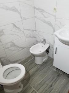 a white bathroom with a toilet and a sink at Sunset House Sarajevo in Sarajevo