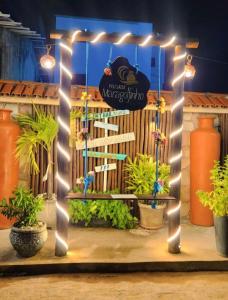 a pergola with lights and a bench in a garden at Pousada Maragolfinho in Maragogi