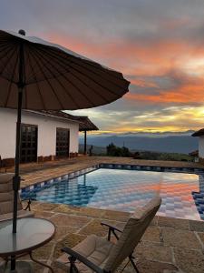 a pool with a table and chairs and an umbrella at Cabaña VillaMaria in Villanueva