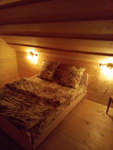 a bed in a wooden room with two lights at Sadyba u Vani in Volovets