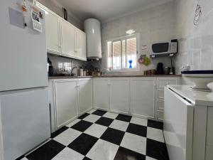 a kitchen with white cabinets and a black and white checkered floor at Isabella Chipiona in Chipiona