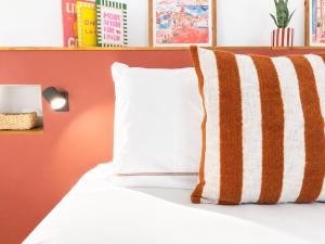 a bed with a white pillow and an orange wall at Le Chabeuillois in Chabeuil +2 photos