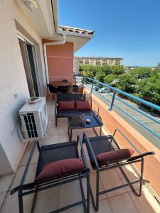 a balcony with chairs and a table and a grill at Appartement frejus in Fréjus