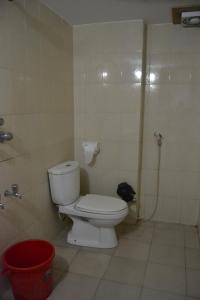 a bathroom with a toilet and a red bucket at Hotel Marine Plaza in Cox's Bazar